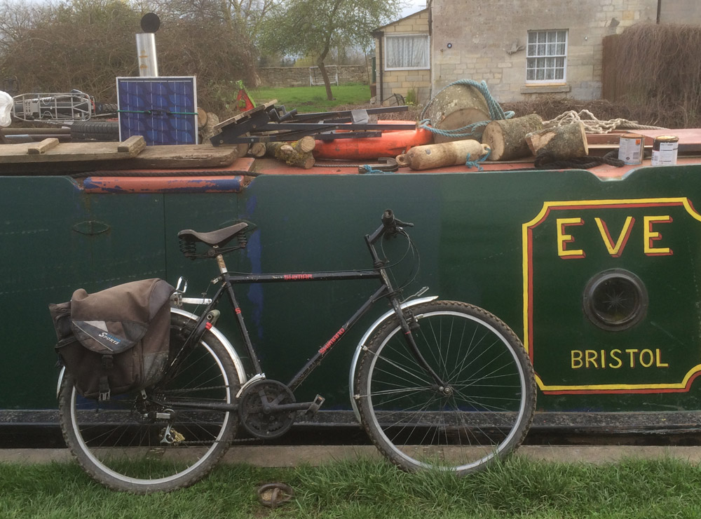 Bicycle propped up against a narrowboat called Eve